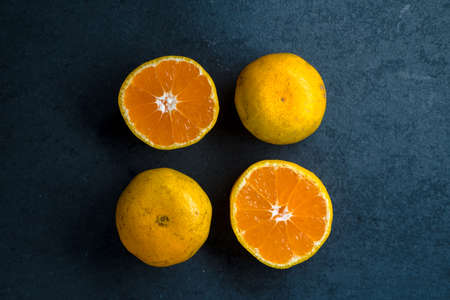 Four halves of an orange on a blue stoneの写真素材