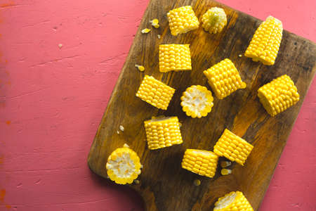 Different pieces of fresh corn on a wooden cutting boardの写真素材