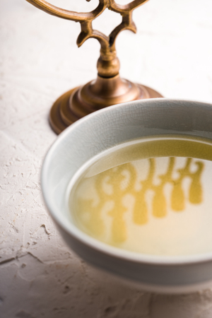 Fragment of Hanukkah and a bowl of olive oil on a white tableの写真素材