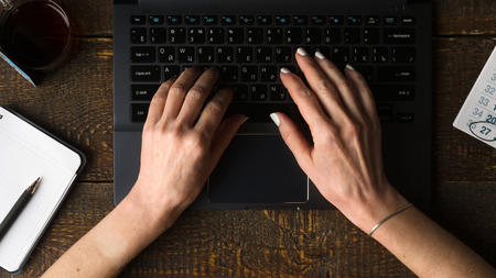 Hands on computer keyboard, notebook and pen view from aboveの写真素材