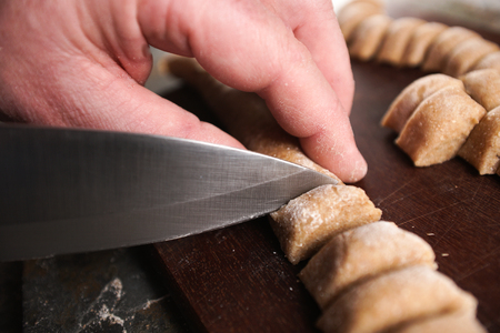 Man slices dough for homemade pasta partial blurの写真素材