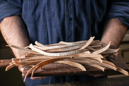 Man holds a wooden board with a paste in his handsの写真素材