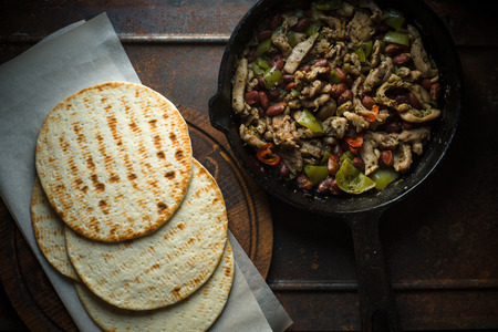 Tortilla on parchment and frying pan with fillingの写真素材