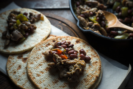Tortilla with filling on parchment and frying pan on the table side viewの写真素材