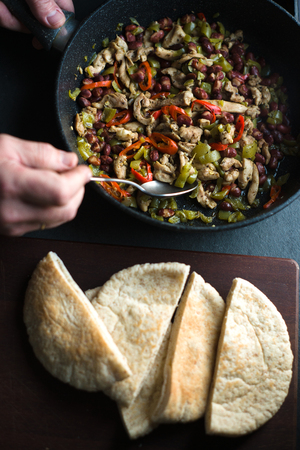 Man is stuffing a tortilla with filling for fajita close-upの写真素材