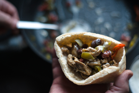 Man is stuffed with tortilla stuffing for fajita partial blurring close-upの写真素材