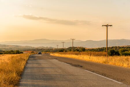 Car on the road and fields in Greeceの写真素材