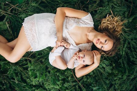 Mom and daughter are lying on spruce branchesの写真素材