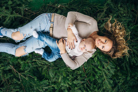 Mom and daughter are lying on spruce branches