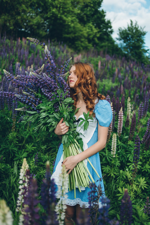 Red-haired women in blue dress with lupinesの写真素材