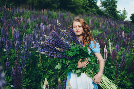 Red-haired women in blue dress with lupinesの写真素材