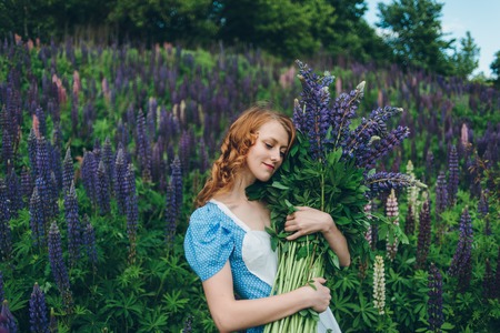 Red-haired women in blue dress with lupinesの写真素材