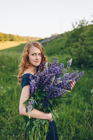 Red-haired women in blue dress with lupinesの写真素材
