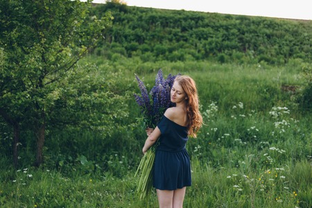 Red-haired women in blue dress with lupinesの写真素材