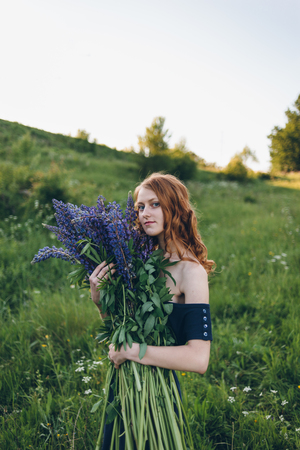 Red-haired women in blue dress with lupinesの写真素材
