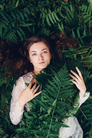 women with red hair in an armful of fernsの写真素材