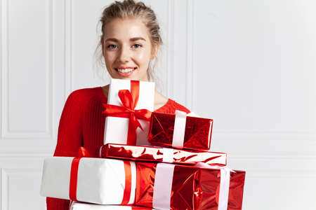 Happy smiling girl with Christmas presents studio headshot. Portrait of beautiful caucasian blond...