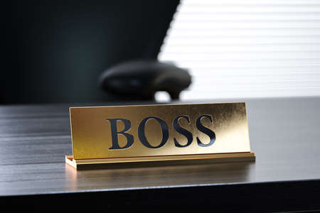 Golden nameplate with Boss text on the wooden table in the office working place, with soft focus depth of field. 3d rendering illustrationの写真素材
