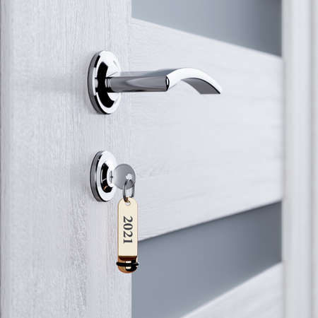 White room door with key in the lock with golden lable number 2021 new year concept