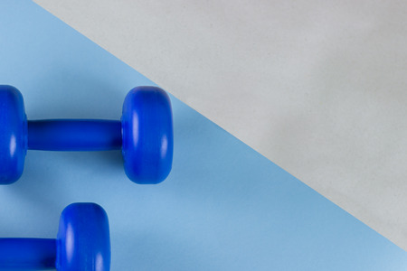 Bright blue dumbbells on a blue background. Healthy lifestyle, the concept of losing body weight. Cares about the body. Empty place for text.の写真素材
