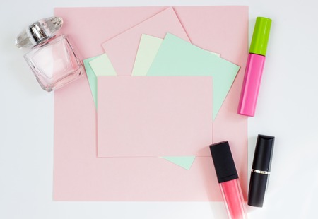 Pink empty card, sheet for writing. Layout for adding tags with perfume and lipstick. Top view, flat lay, copy space.の写真素材