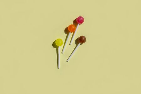 Multi-colored lollipops with hard shadows on a yellow background. Layout for recording. Flat lay, top view.の写真素材