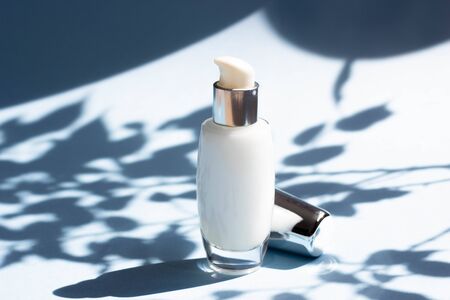 Face cosmetics. Jars of cream, face mask on a blue background with hard shadows from the leaves. Beauty blogger, procedures salon concept. Minimalismの写真素材