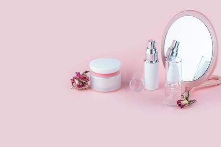 Face care cosmetics. Jars of cream and face serum on a pink background. Beauty Salon Concept.
