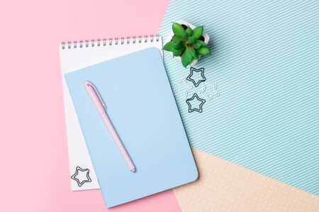 Flat lay of a female workplace. Notebook, pen and flowers on a pink and blue background. Design blog and social networksの写真素材