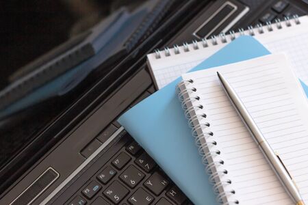 Workplace with laptop, notebook and glasses on a wooden table. Work from home. Blurred background.の写真素材