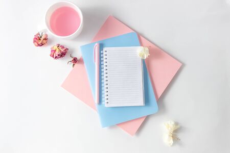 Female workspace with empty open notebook for writing, pen on a white table. Top view, flat lay, copy space, minimalismの写真素材
