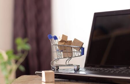 Online shopping with home delivery. Shopping basket and boxes on laptop keyboardの写真素材