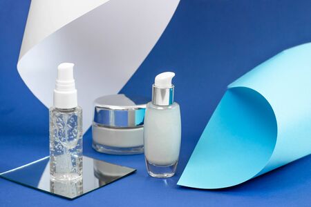 Cosmetic bottles with serum, gel, face cream on a blue background. Skin cosmetics, minimalism. The concept of salon proceduresの写真素材