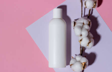 Natural cosmetics in a white bottle top view on a pink background