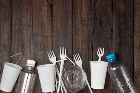 Plastic dishes, bottles, glasses on a white table. Planet pollution.