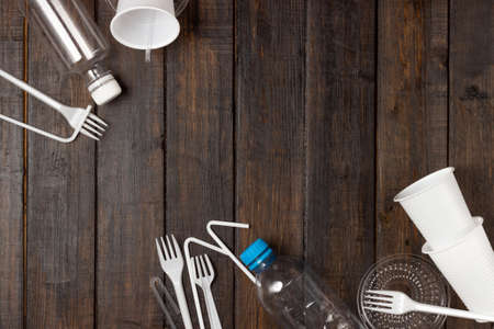 Plastic dishes, bottles, glasses on a white table. Planet pollution.