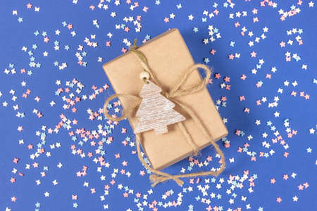 Gift box wrapped in kraft paper on a blue background. Top view, holiday concept.