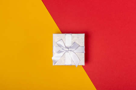 Gift box on a bright red and yellow background. Top view, holiday concept.
