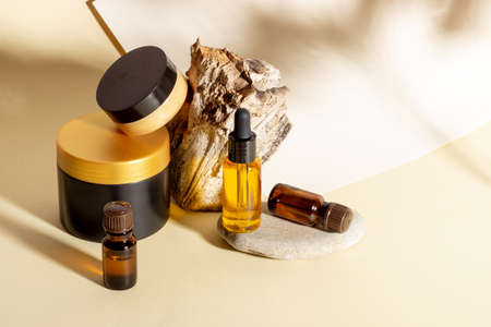 A set of cosmetic products next to a log and hard shadows on a beige background. Natural organic cosmeticsの写真素材