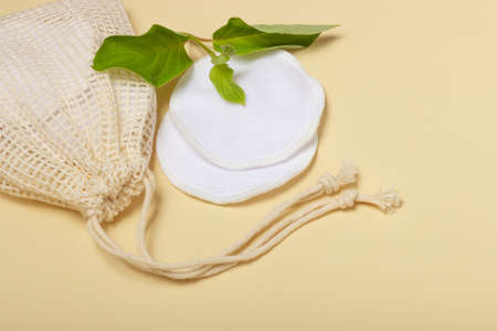 Cotton reusable makeup remover pads in a cloth bag on a beige background. Reusable cotton padsの写真素材