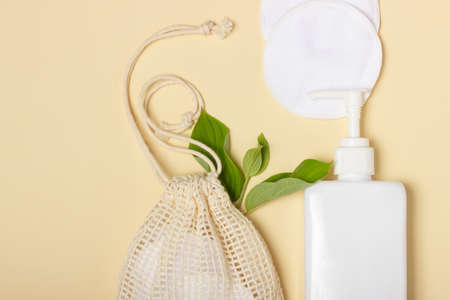 Cotton reusable makeup remover pads in a cloth bag on a beige background. The concept of ecology and...