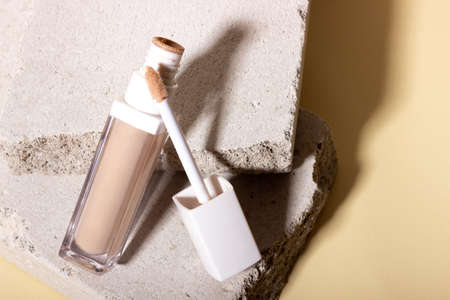 Foundation, concealer on a background of concrete geometric shapes. Face corrector on beige background with copy space. Packaging mockup with copy spaceの写真素材