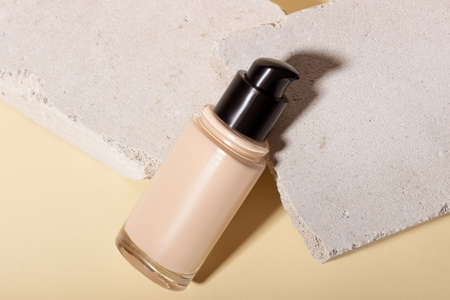Foundation, concealer on a background of concrete geometric shapes. Face corrector on beige background with copy space. Packaging mockup with copy spaceの写真素材