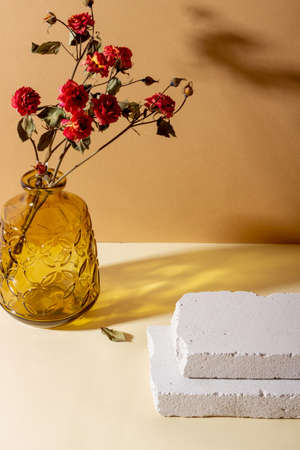 Background with geometric shapes made of concrete for cosmetic products. Rectangular podiums, glass vase with dried flowers and shadows on a beige background. Blank mockup for productの写真素材