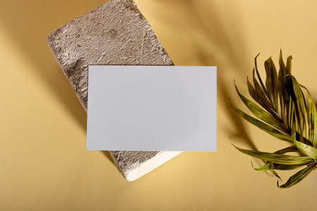 Mockup with blank horizontal paper cards with copy space on a plinth with palm leaves. Hard sunlight and shadows on a beige background. Minimal template for business layout. Top view, flat layの写真素材