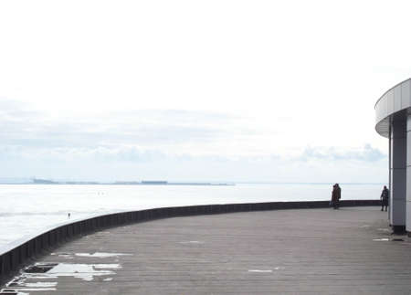 Two people are walking. Spring day, the Gulf of Finland. They go into the distance.