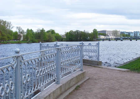Summer in the park. A metal fence by the river.の写真素材