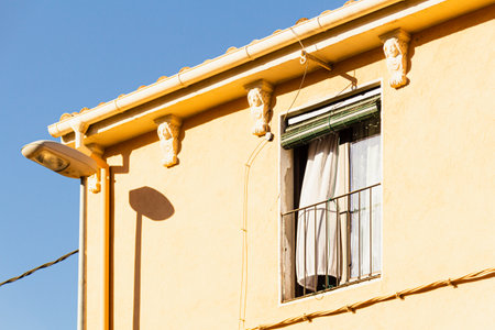 Open window with curtain on a sunny day in Spain. Yellow house type Spanish - Italian - French. South European architecture.の写真素材