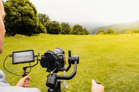 Stabilized camera on a gimbal / steadicam recording a scene. Photograph taken from behind and up close while the operator operates the camera.の写真素材