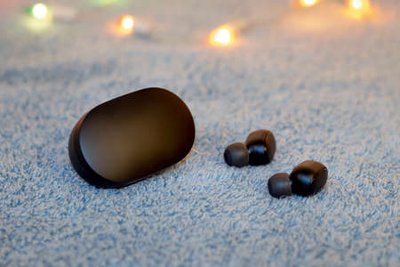 cute black wireless headphones with charging case on a gray plush background